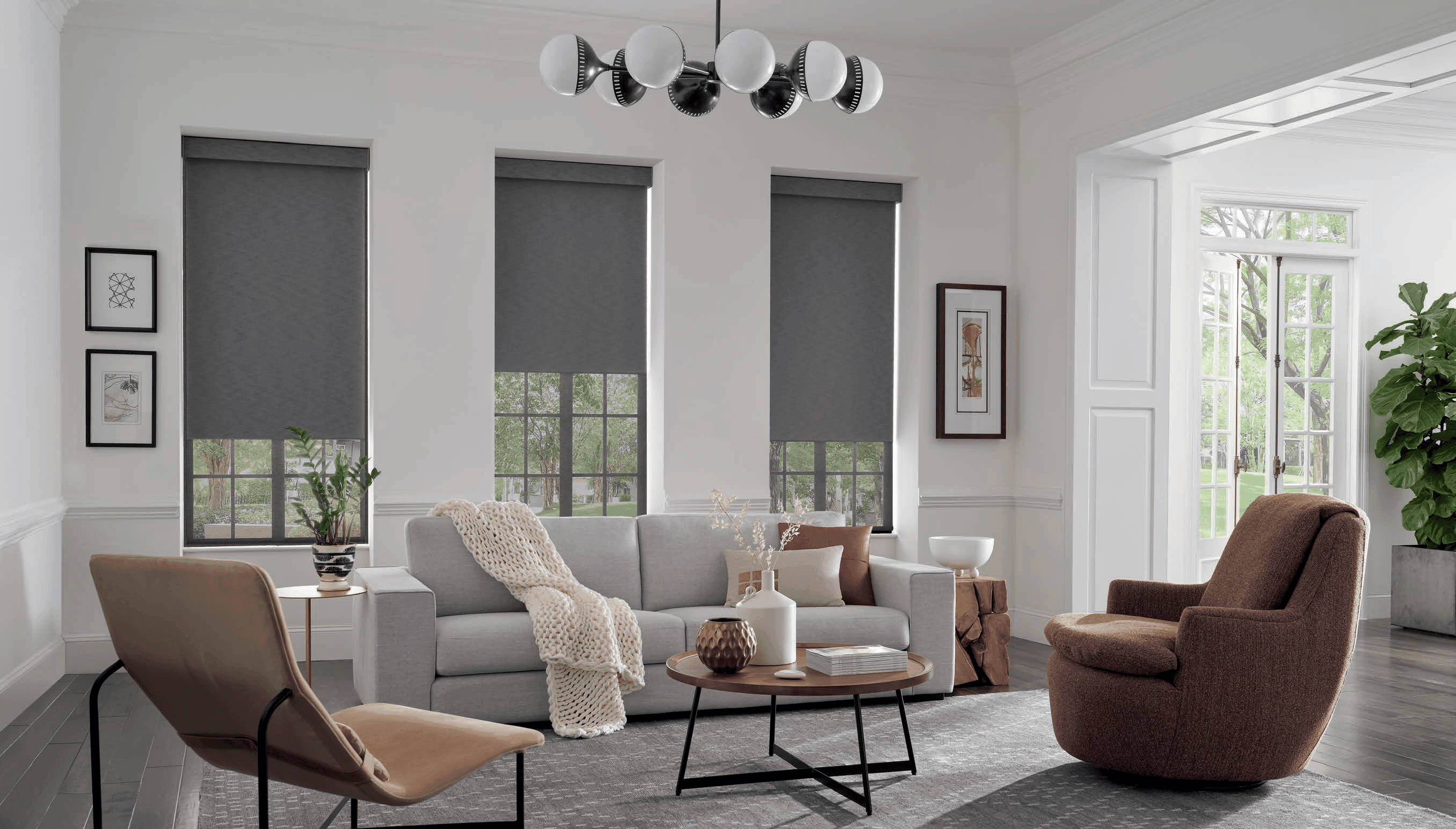Grey roller shades on three tall living room windows